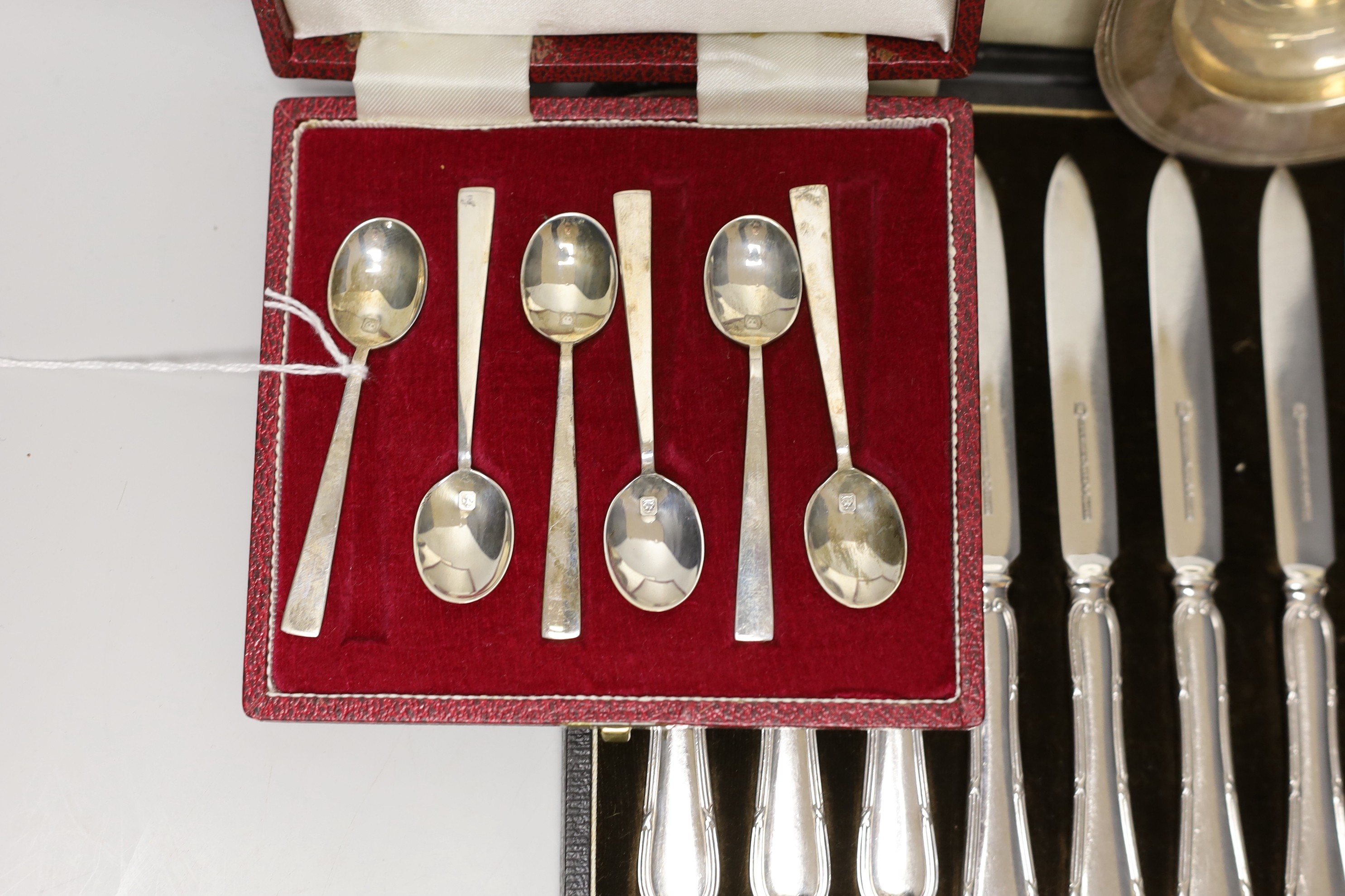 A cased set of six silver coffee spoons, a cased set of six silver-handled dessert knives, a small silver dish and a cased set of plated dessert knives and forks